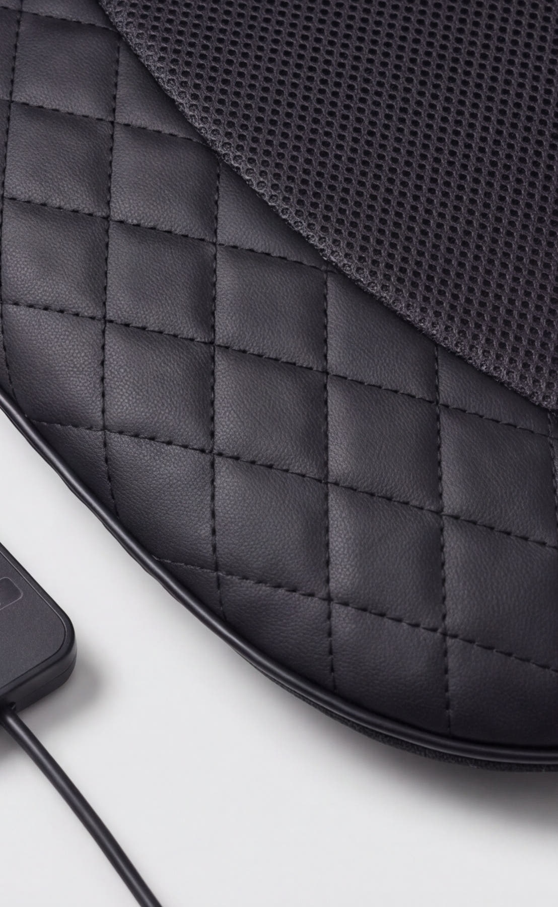 Close-up of the massage seat pad's quilted leather and mesh fabric texture