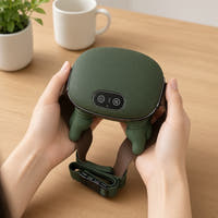 Hands holding the green cordless trapezius massager with strap on a table